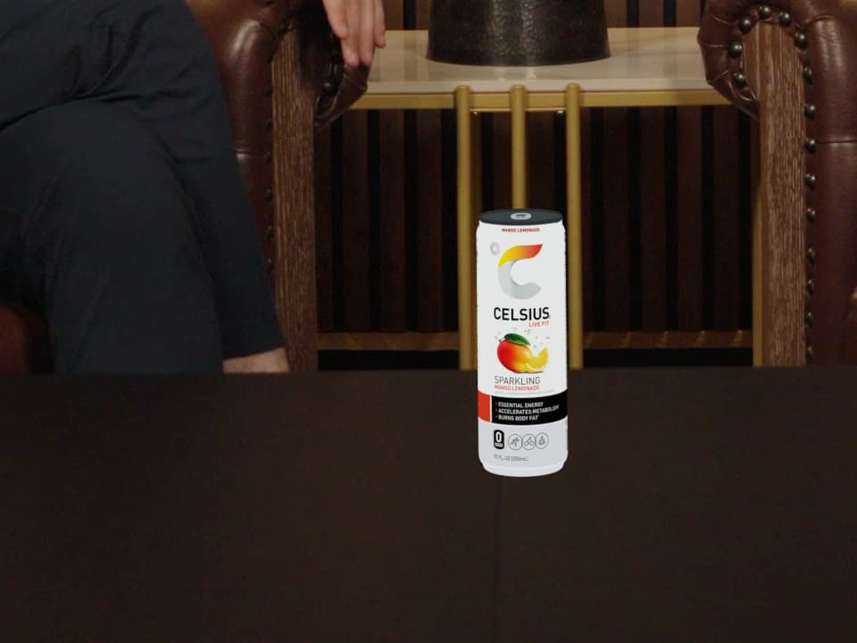 Close-up of a Celsius can on a dark wooden table, bright white and evenly lit, with no shadow
